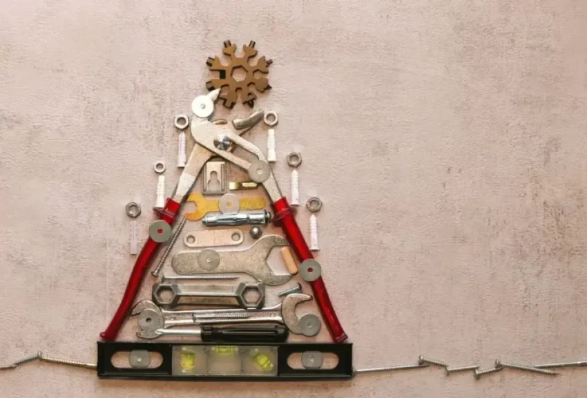 Dispositif d'outils metalliques disposes en triangle sur mur rose, avec pinces rouges et barbeles au pied.